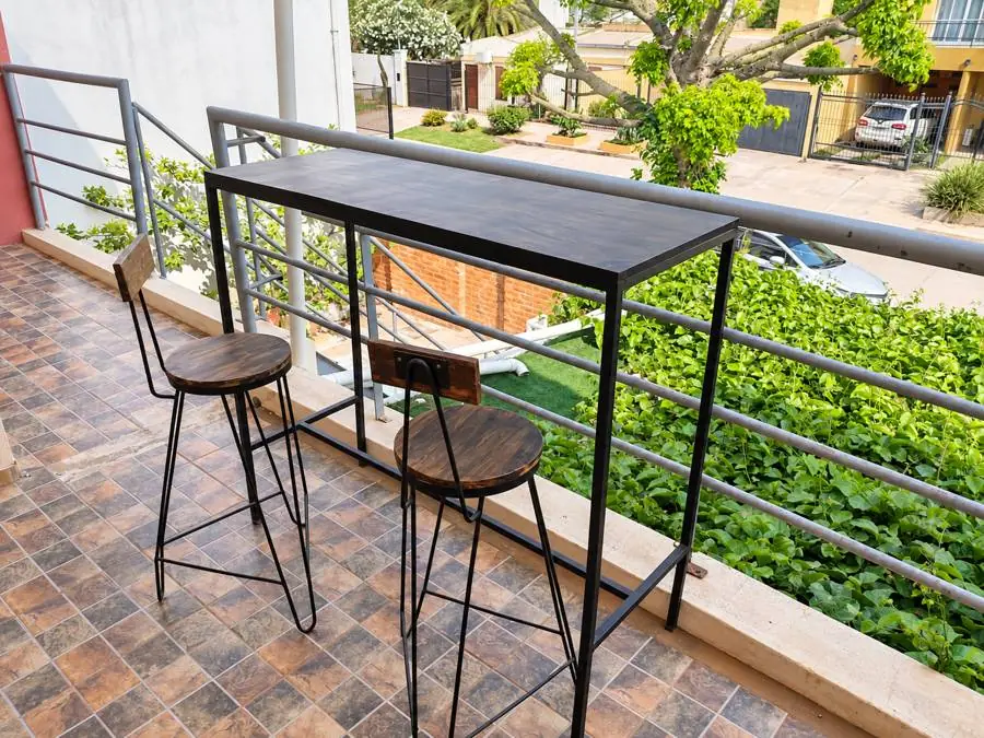 Terraza con mesa alta y dos banquetas de madera y hierro