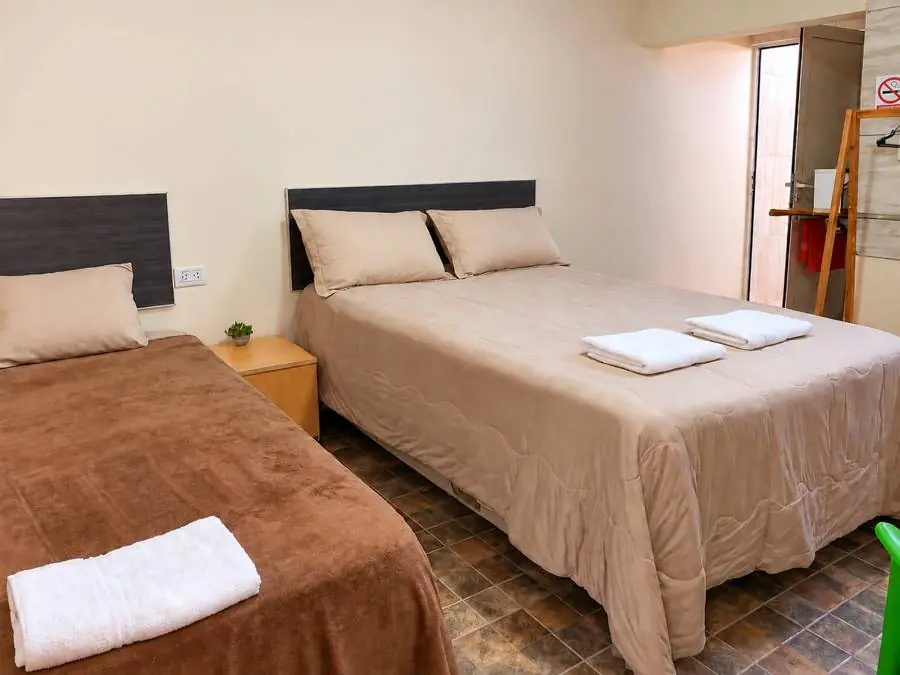 Habitación con cama grande, otra cama individual y mesita de luz