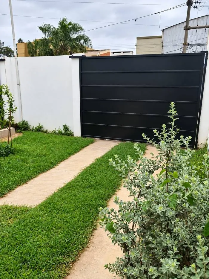 Sendero de cemento y césped hacia el portón